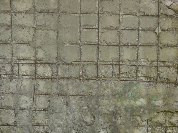 Concrete slab texture with very old, damaged surface and rusty, metal armature laid across slab.