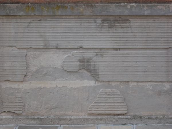 Concrete wall texture with lined patterns on surface. Concrete is slightly damaged.