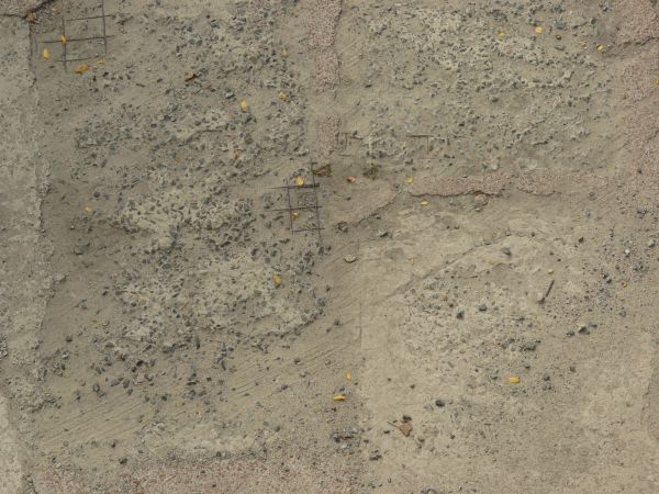 Rough concrete floor texture with rocks and damaged surface exposing armature.