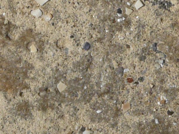 Beige concrete floor consisting of stones of mixed colors and sizes on surface.