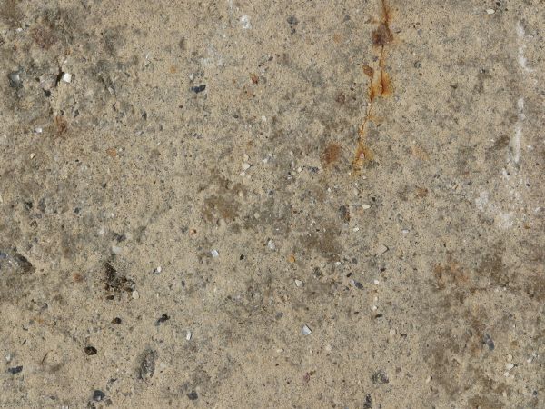 Beige concrete floor consisting of stones of mixed colors and sizes on surface.