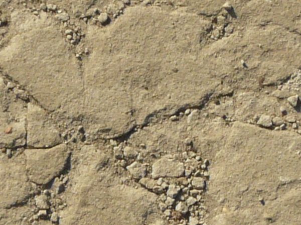 Worn concrete floor texture in beige color with very rough surface and cracks throughout.