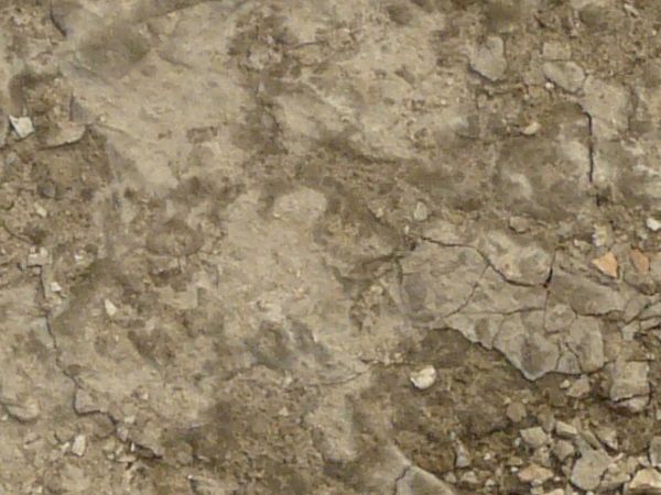 Concrete ground texture in light beige tone with very rough, damaged surface.