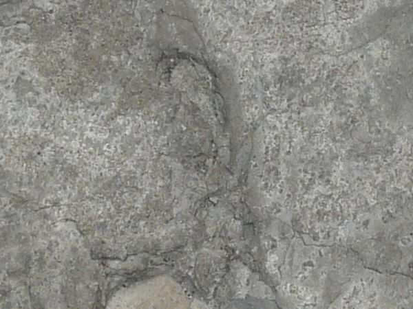 Ground made of concrete in grey tone with irregular surface and cracks.