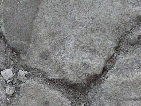 Old concrete floor texture in consistent, grey color with myriads of thick cracks throughout.