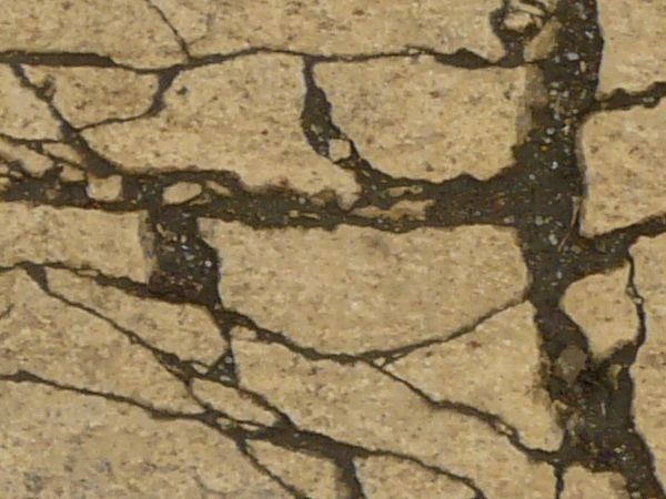 Cement texture with rough surface and large amount of cracks and dark dirt in cracks.