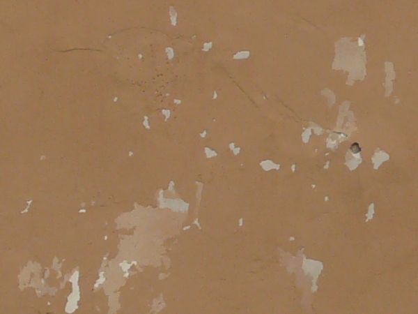 Solid surface covered in thin layer of pealing, brown paint.