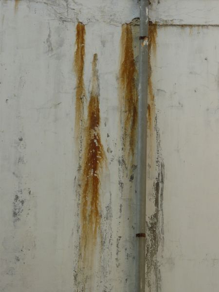 Concrete texture in off-white color with rough surface and streaks of rust.