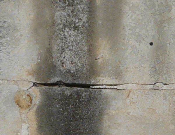 Texture of old concrete in beige tone on bottom with thick, black and white streaks and spots.