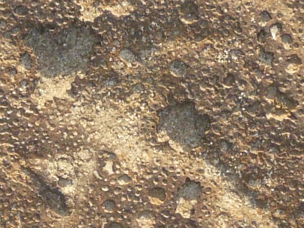Rough metal texture in shiny, bronze tone with small craters and scratches on surface.