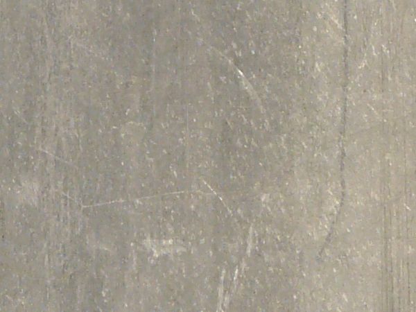 Slightly worn stainless steel surface with light streaks and scratches.