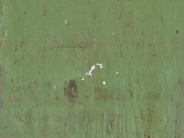 Worn metal surface painted in pale-green color with scratches and dents.