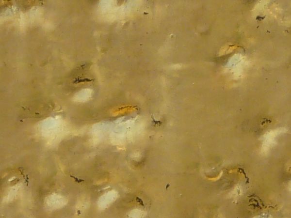 Shiny metal texture in gold color with large amount of dents in surface.