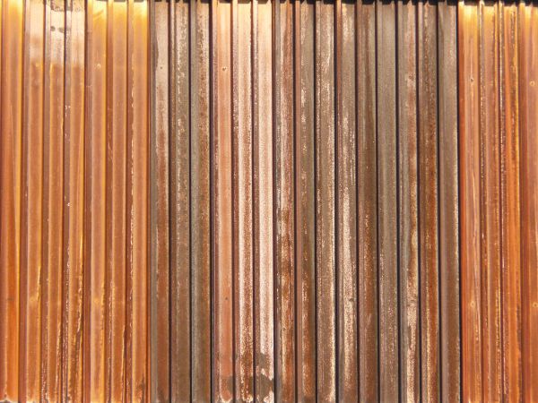 Aged texture consisting of lined, metal siding with worn, rusting surface.