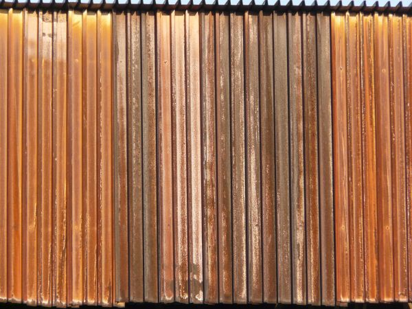 Aged texture consisting of lined, metal siding with worn, rusting surface.
