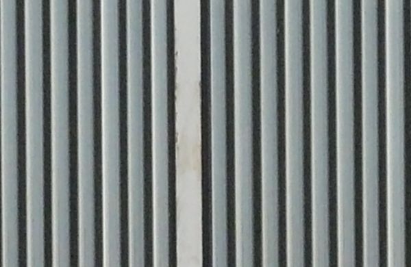 Metal texture of aluminum siding in grey color with lined surface and white, metal framing.