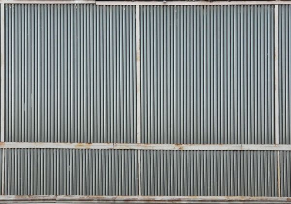 Metal texture of aluminum siding in grey color with lined surface and white, metal framing.