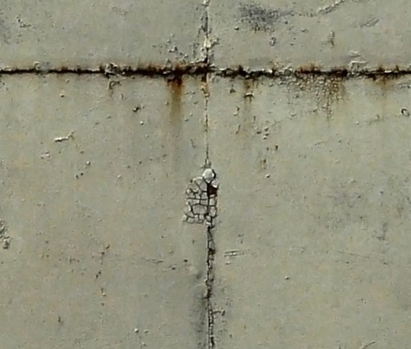 Aged texture of worn sheet metal in grey color with dents, scratches and spots of rust.