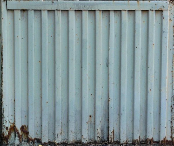 Aged metal siding in light blue color with lined texture and rusting surface.
