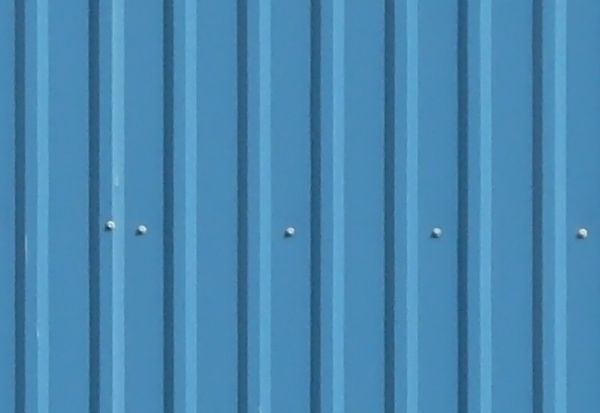 Texture of new metal siding painted in blue with lined texture.