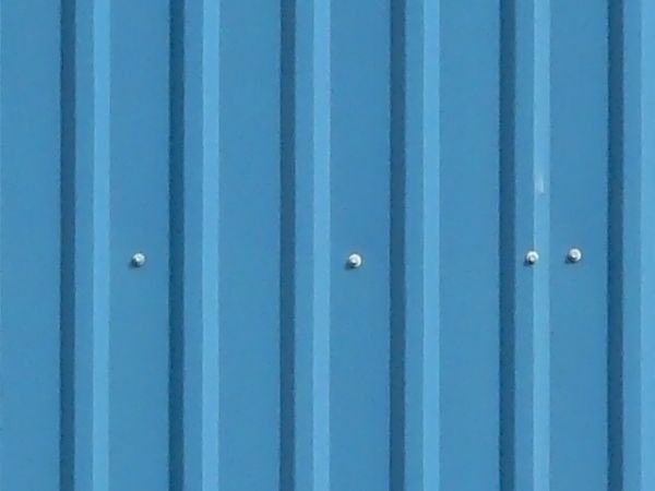 Texture of new metal siding painted in blue with lined texture.