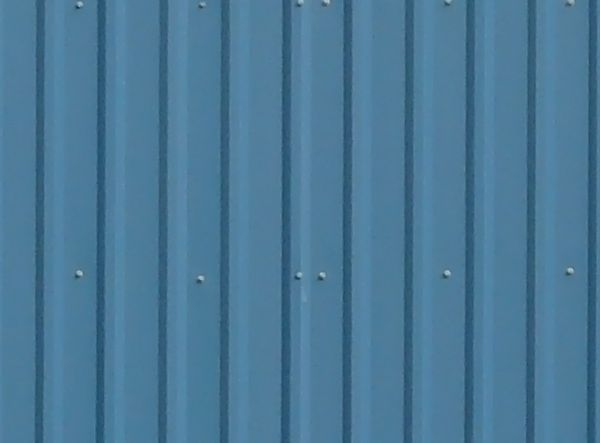 Texture of new metal siding painted in blue with lined texture.