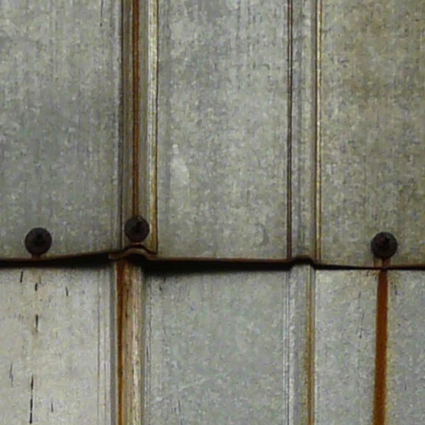 Aluminum sheet metal panels with lined texture and streaks of rust coming from nails.