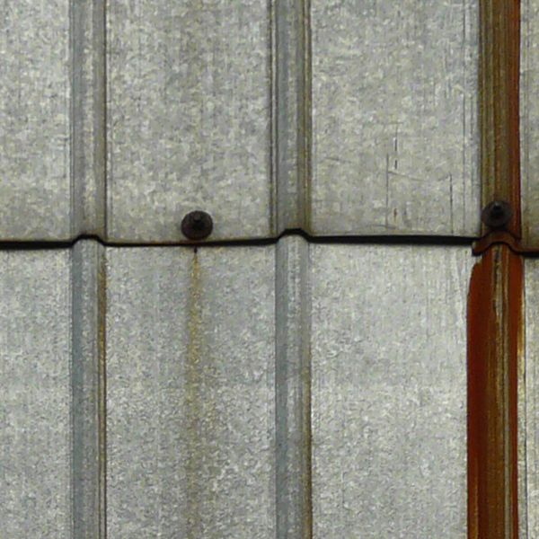 Aluminum sheet metal panels with lined texture and streaks of rust coming from nails.