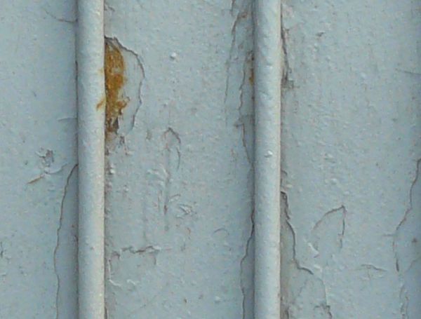 Metal texture in light blue color with worn surface and vertical rods at regular intervals.