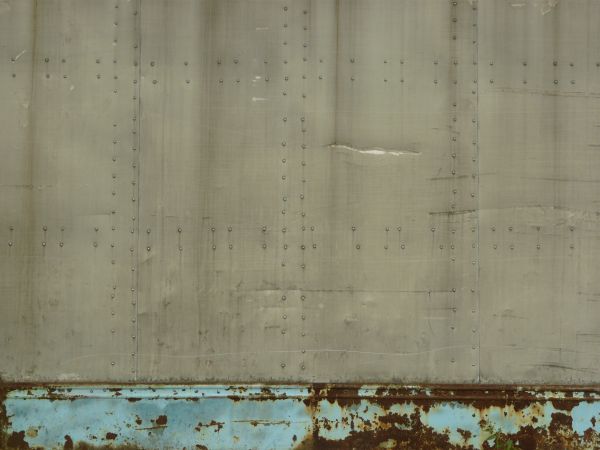 Slightly worn metal texture in grey tone with dents and nails in surface.