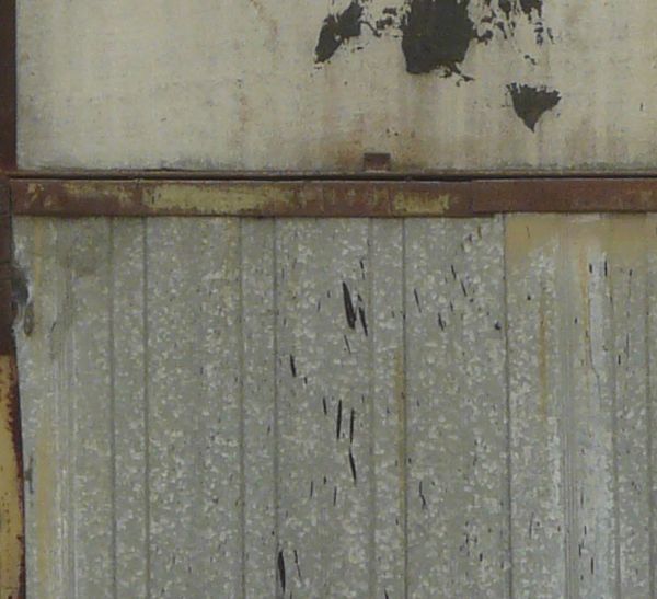 Large metal panels with damaged, rusting surface.