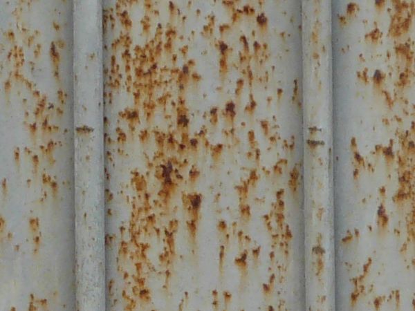 Metal siding with lined texture and very worn, rusting surface.