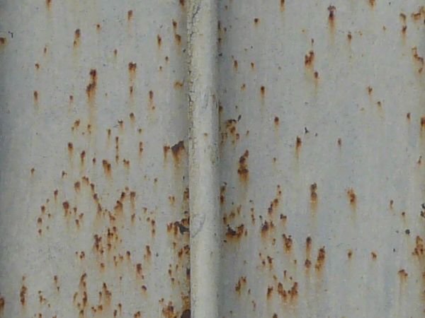 Metal siding with lined texture and very worn, rusting surface.