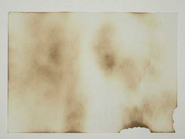 White paper texture with irregular patches of brown stains, and small burned edges in the bottom-right corner.