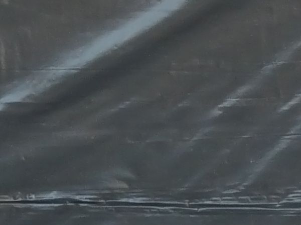 Plastic tarp in black tone with wrinkled surface.