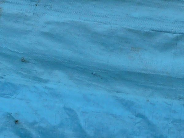 Plastic tarp in blue tones with dirty surface and wrinkles.