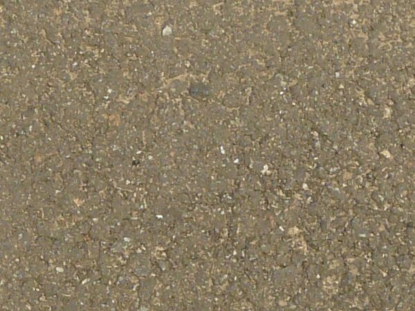 Road texture, sandy brown in color, with a large, irregularly shaped patch of dark asphalt on the center.