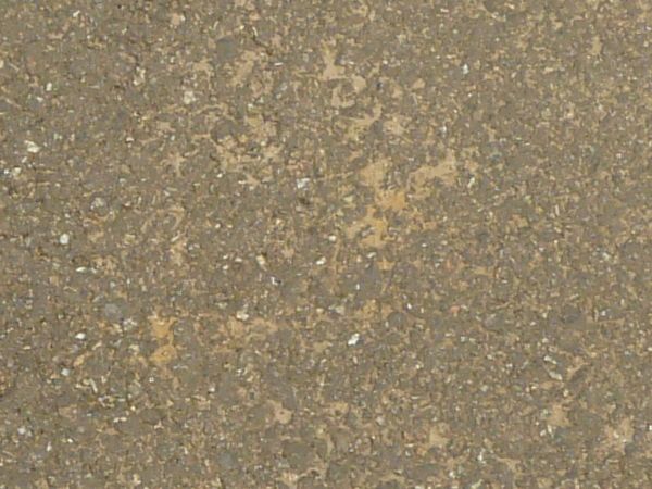 Road texture, sandy brown in color, with a large, irregularly shaped patch of dark asphalt on the center.