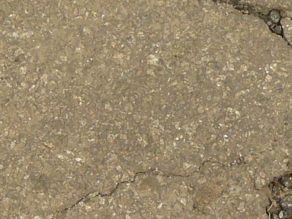 Road texture, brown in color, with a small hole worn into the center with crumbling rock and thin cracks surrounding it.