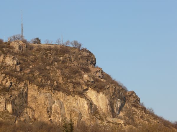 Landscape with jagged rock cliffs in brown tones and long, dry grass throughout.