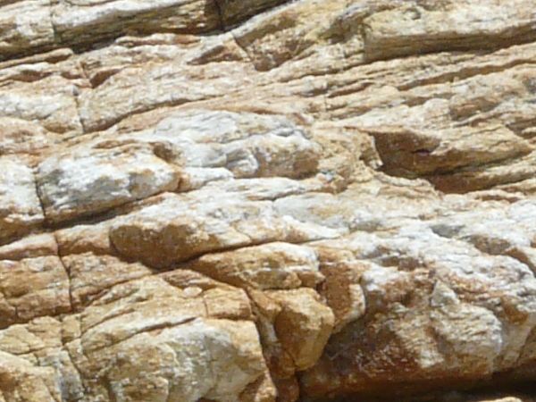 Rock cliff texture in brown and grey tones consisting of rough, layered rock.