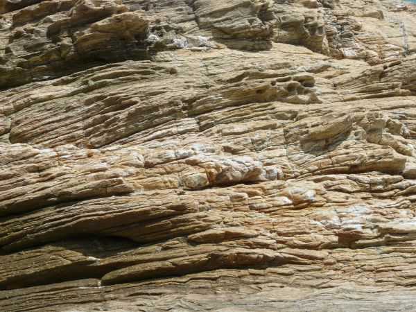 Rock cliff texture in brown and grey tones consisting of rough, layered rock.