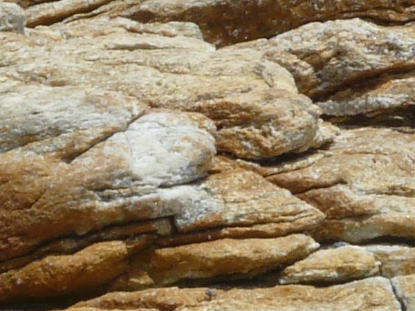 Rock cliff texture in brown and grey tones consisting of rough, layered rock.