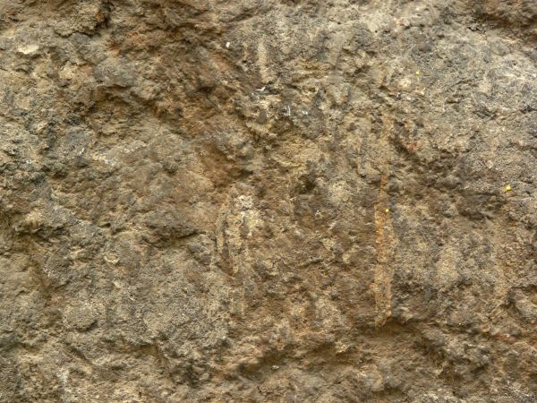 Seamless texture of natural stone in brown and grey tones with very rough, uneven surface.