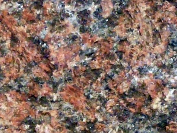 Granite texture in mixed tones of red and black with uneven, rugged surface.