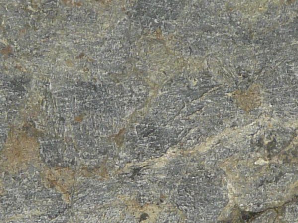 Stone surface in light grey tone with large cracks and dirt in cracks.