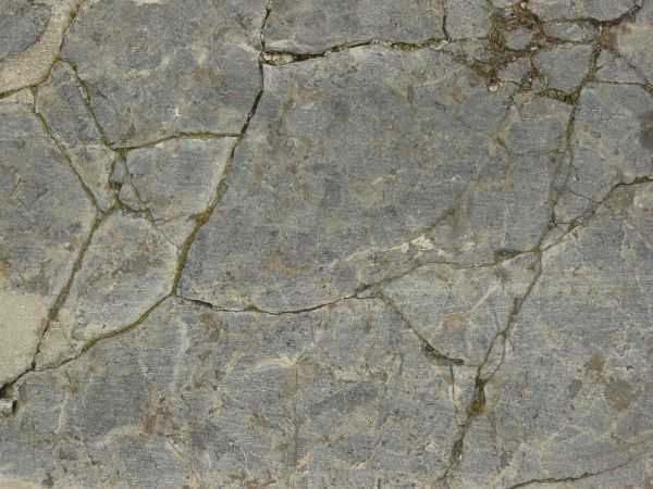 Stone surface in light grey tone with large cracks and dirt in cracks.