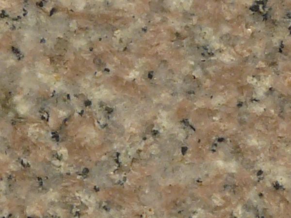 Texture of flat, grained granite in beige tones with slightly rough surface and small pigments of black.
