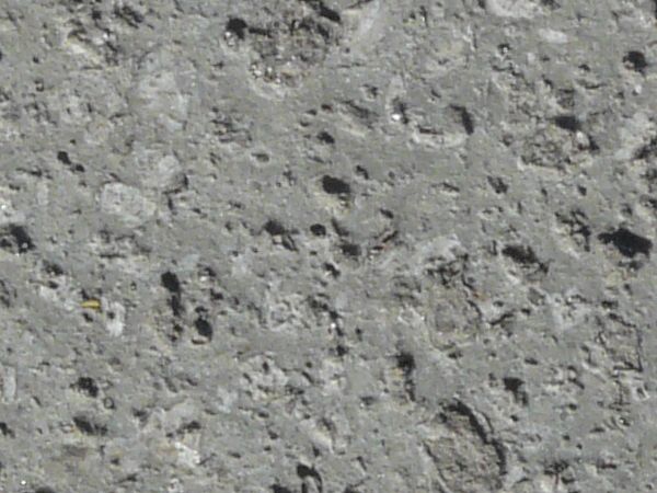 Flat stone texture in consistent, grey tone with small holes throughout surface.