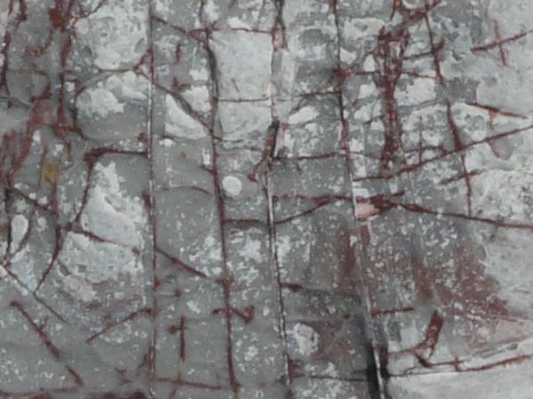 Stone texture in light grey tones with myriads of cracks across flat surface.